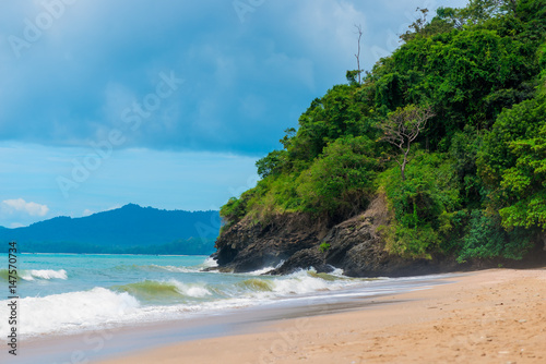 Sandy beach and cliffs of Thailand in inclement weather, dark blue sky over the sea