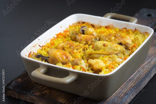 Chicken curry and rice in a ceramic baking dish on a dark background