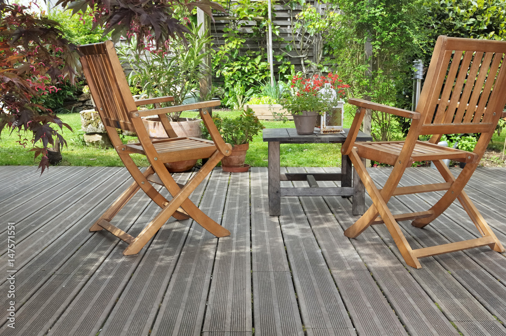 chaises et table sur terrasse en bois donnant sur jardin  - obrazy, fototapety, plakaty 
