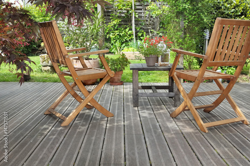 chaises et table sur terrasse en bois donnant sur jardin 