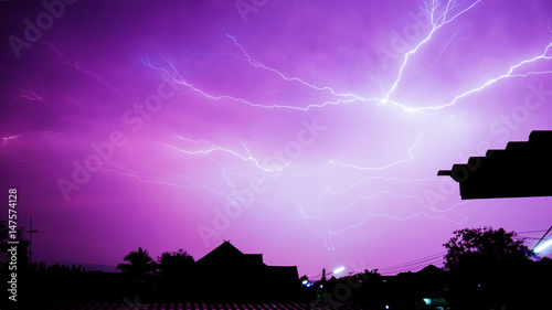 More lightning in the night sky near house.