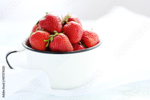 Strawberries in cup on blue wooden table