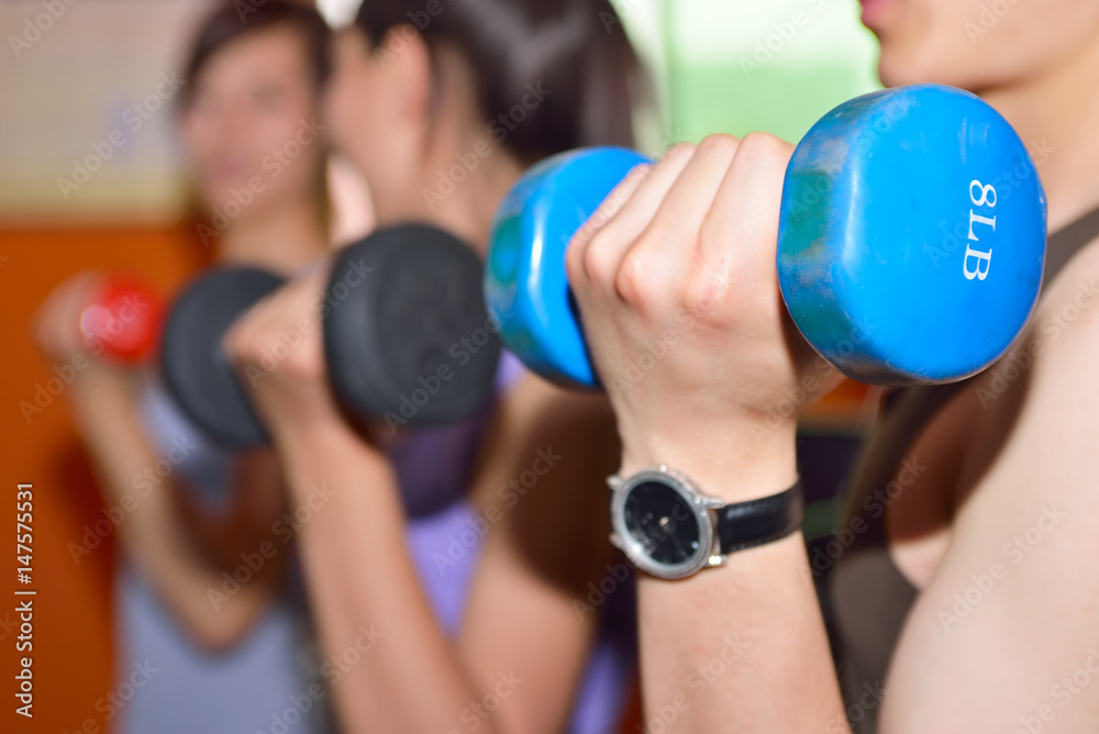 Young people exercise in the gym, using dumbbells