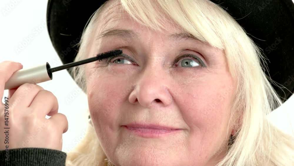 Applying makeup on old woman. Hand with eyelash brush. Applying makeup on old woman. Hand with eyelash brush.