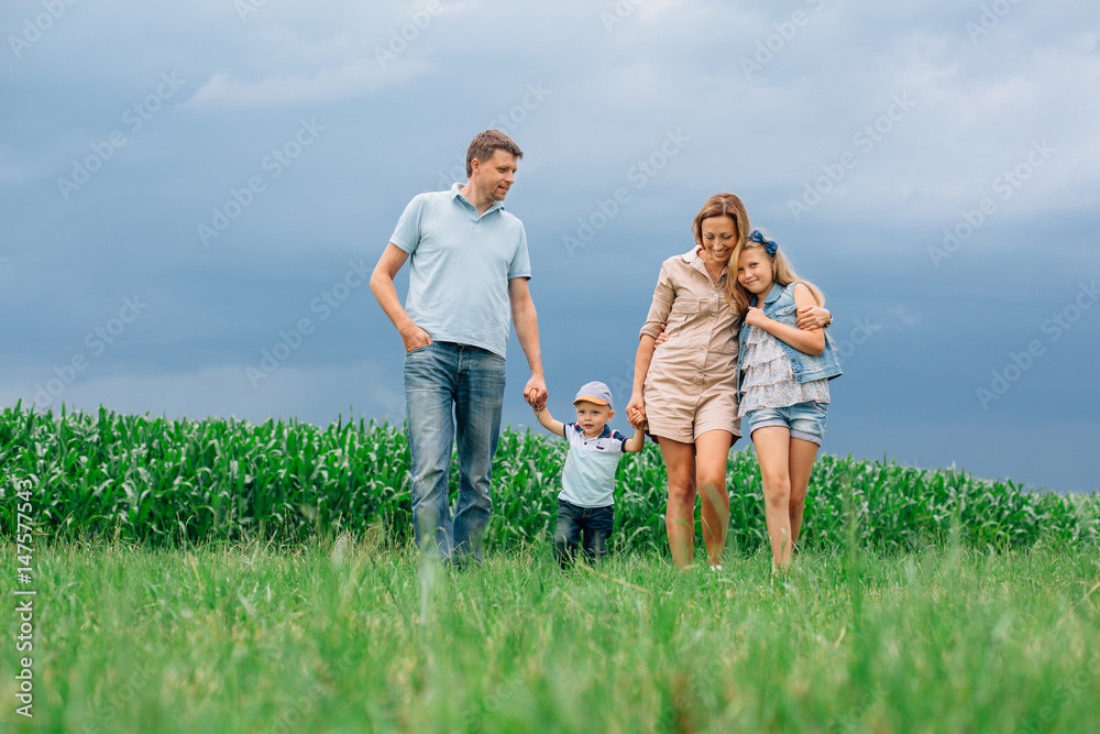 Happy family of four walking through the field. Mother father son daughter Smiling and laughing. Girl with parents and her little brother Happy family of four walking through the field. Mother father son daughter Smiling and laughing. Girl with parents and her little brother
