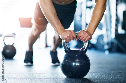 Unrecognizable fit man in gym doing push ups on kettlebells