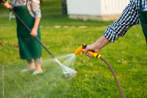 Senior hand holding water hose. Garden hose sprayer. Lawn care tips. © DenisProduction.com