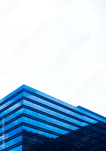 Top of mirrored building against cloudy sky background
