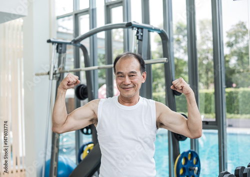 Asian Senior Man Posting To Show His Muscle in The Gym After Workout - Sport and Healthcare Concept
