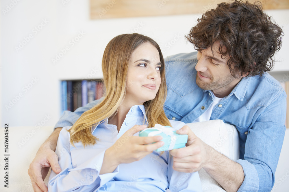 Lovely young couple with a surprise gift. Shot of a happy young woman opening the gift box while handsome smiling man standing behind her. Lovely young couple with a surprise gift. Shot of a happy young woman opening the gift box while handsome smiling man standing behind her.