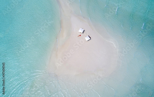 Sandbank in den Malediven mit Sonnenschirmen und Frau die sich sonnt