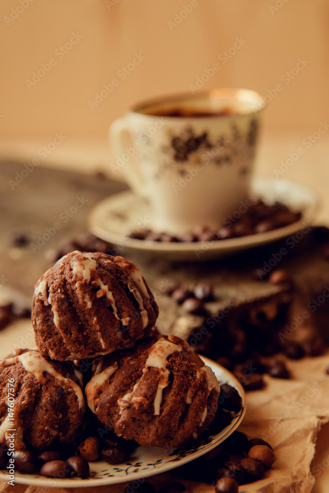 Fototapeta premium Sweet cake with a cherry and coffee beans on background of cup of coffee and warm knitted scarf. Tasty food background. Cozy winter breakfast. Good morning.