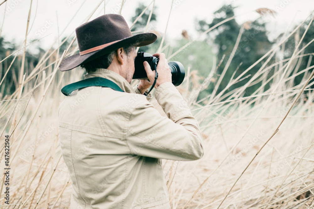 Obraz premium Rear view of man with hat photographing nature.