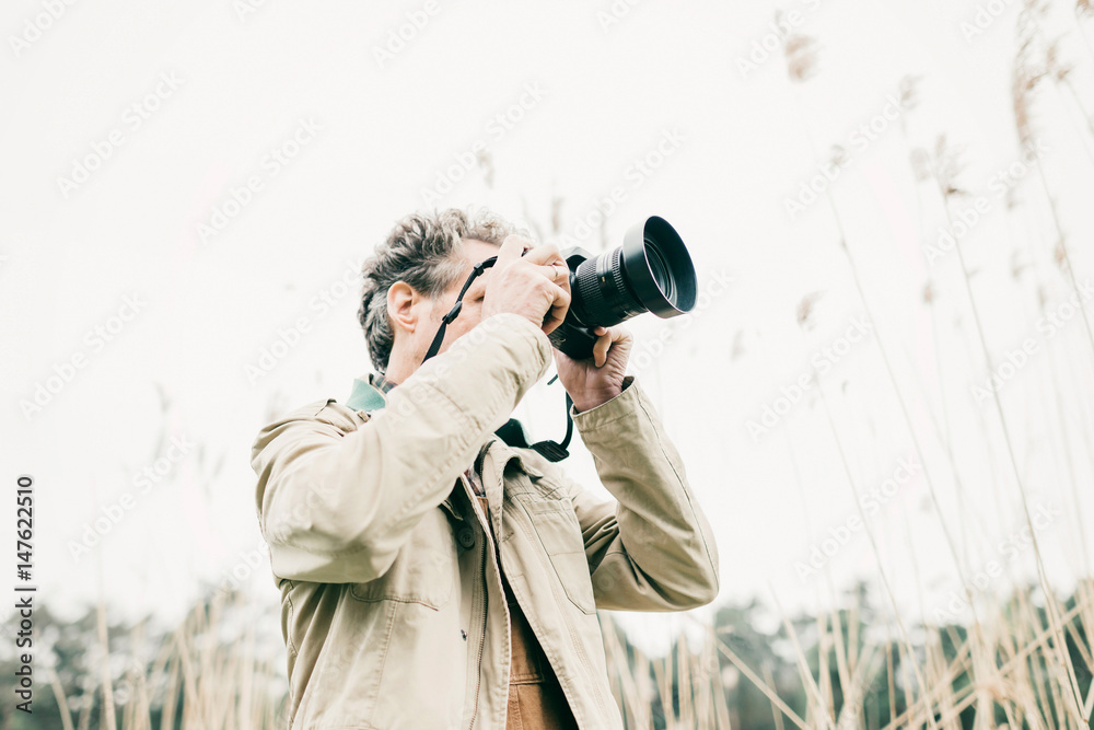 Obraz premium Man taking pictures of nature. Standing between reed.