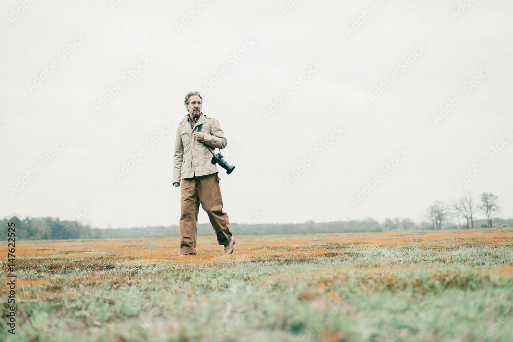 Man with camera walking over grassy land. Man with camera walking over grassy land.