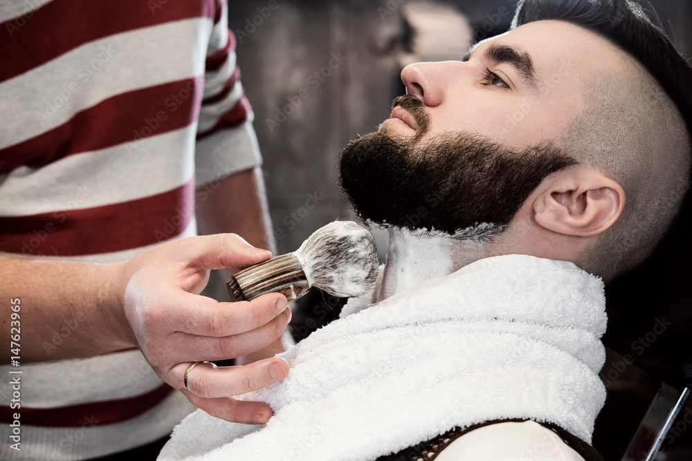 Hairdresser man shaves a client with a beard in a barbershop Hairdresser man shaves a client with a beard in a barbershop