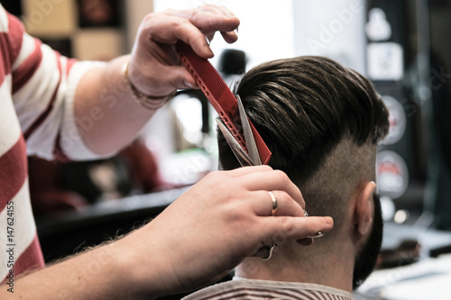 Hairdresser man shaves a client with a beard in a barbershop