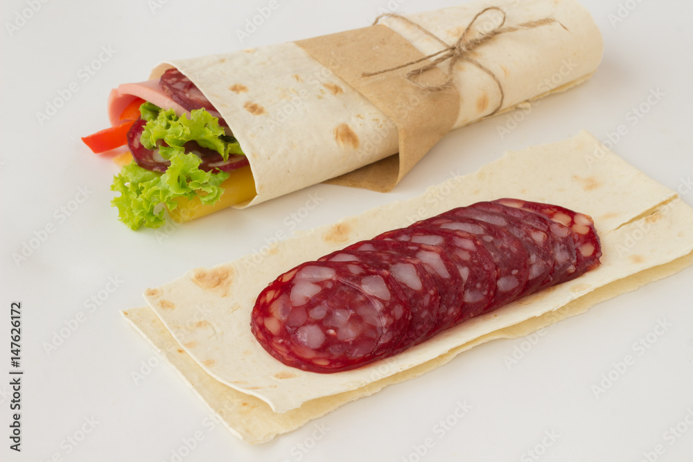 Roll tortilla with herbs, cheese and meat on a white background. Roll tortilla with herbs, cheese and meat on a white background.
