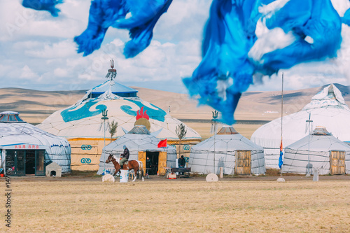 20140924_Inner mogolia,China a mogolian local ride a horse in front of group of yurts in mongolia ,in grassland with blue sky photo