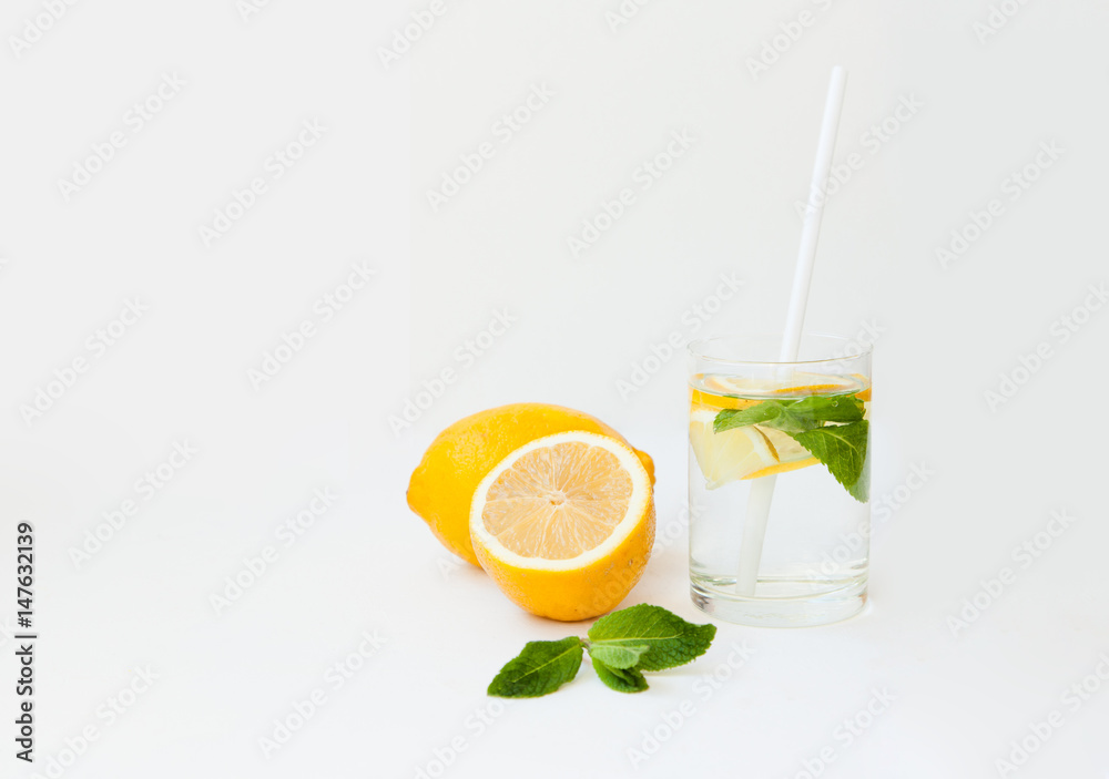 Homemade lemonade with water, lemon and mint leaves in a glass on a white background. Homemade lemonade with water, lemon and mint leaves in a glass on a white background.