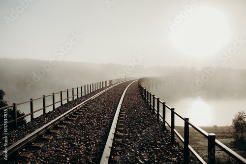 Railway bridge over a river in a foggy day. © daviles