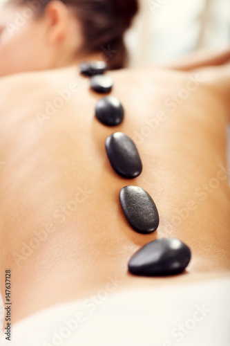 Beautiful woman getting stone massage in spa