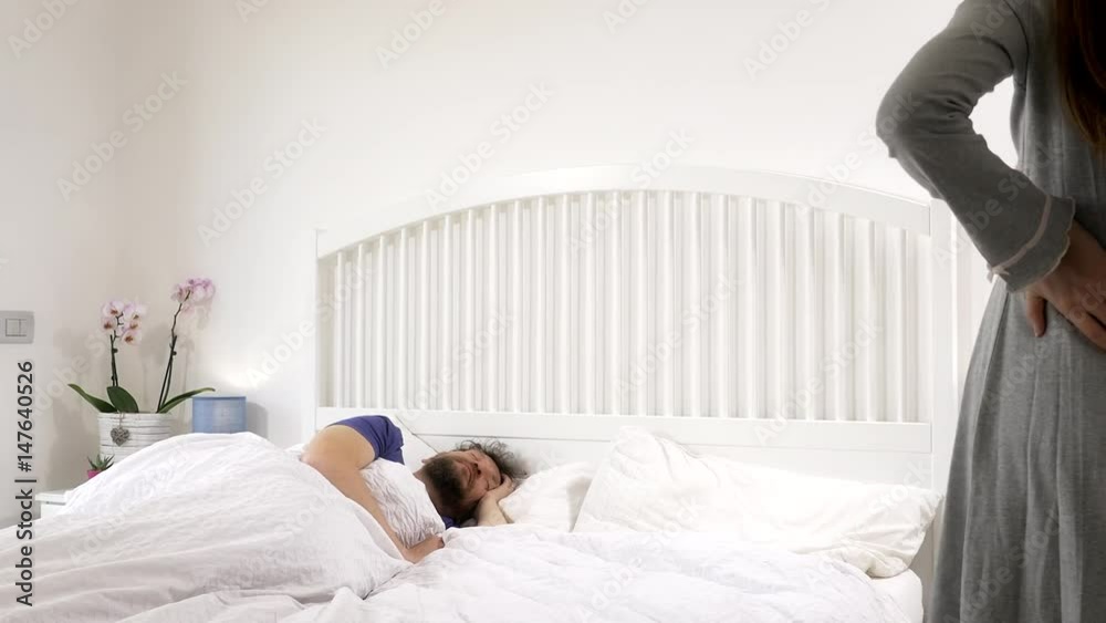 Angry nervous pregnant woman waking up husband in bed medium shot Angry nervous pregnant woman waking up husband in bed medium shot