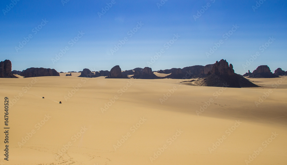 Cars passing through a desert plateau in  South Algerian Desert -Tassili N'ajjer