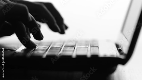 Silhouette video of female hands typing by fingers on netbook keyboard entering a request on the Internet, communicating in social networks, ordering services, working in the office