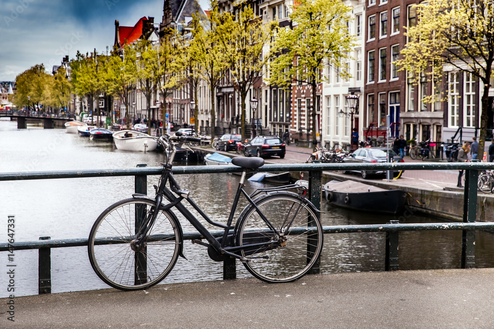 Black bicycle on the bridge on the canal of Amsterdam, Netherlands