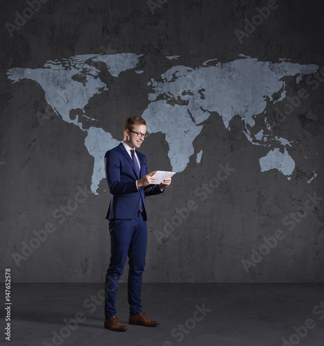 Businessman standing with computer tablet. World map background. Business, globalization, concept.