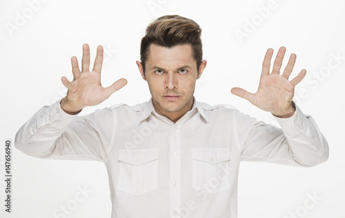 Handsome young man making furious face, with hands on head, isolated on white © serhii