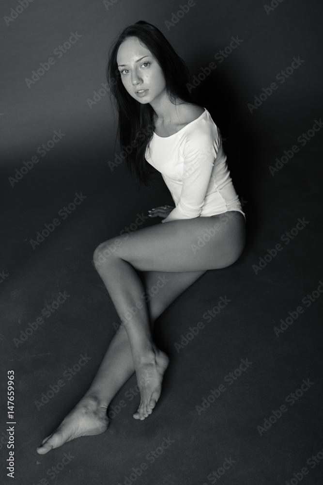 Black-and-white photo of a young brunette white body sitting on the floor