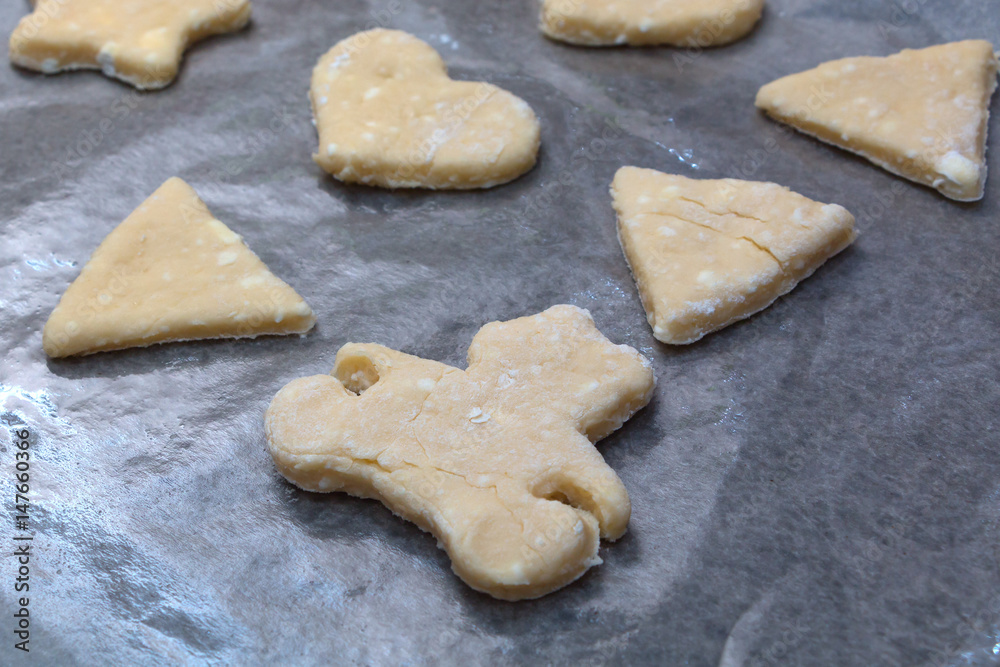 Cookie dough in different shapes lies on the baking sheet. Cookie dough in different shapes lies on the baking sheet.