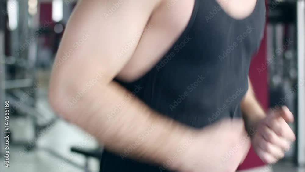 Young athletic men and women exercising and running on treadmill in sport gym. Shot in 4K