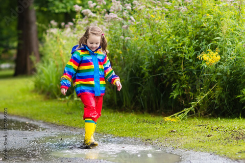 Fototapeta Naklejka Na Ścianę i Meble -  Kids play in rain and puddle in autumn
