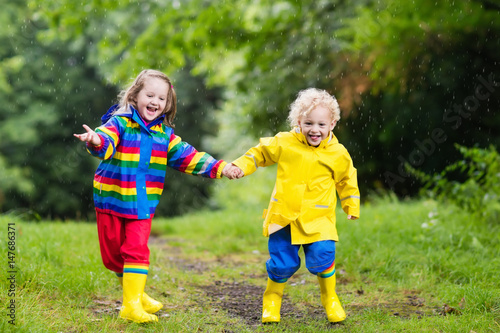 Kids play in rain and puddle in autumn © famveldman