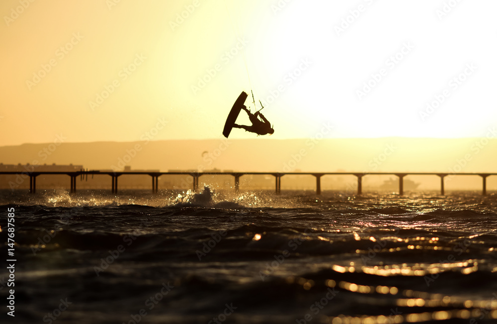 Kiteboarding sportsman silhouette, sunset in the sea