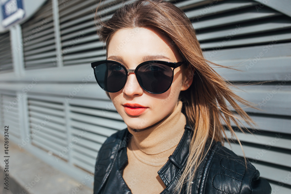 Fashion portrait pretty woman in black rock style in sunglasses over gray background in city Fashion portrait pretty woman in black rock style in sunglasses over gray background in city