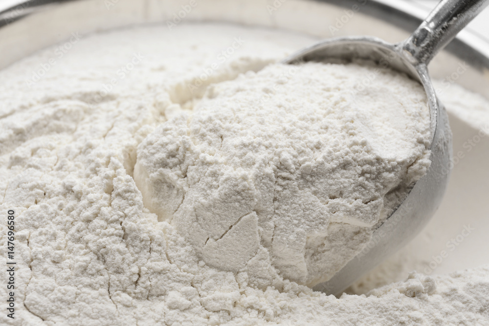 Taking wheat flour from bowl, closeup