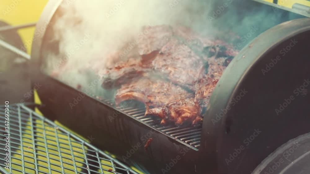 Cooking / smoking delicious juicy meat steaks and sausages on the grill on fire and Barbecue Smoker for smoke roasting