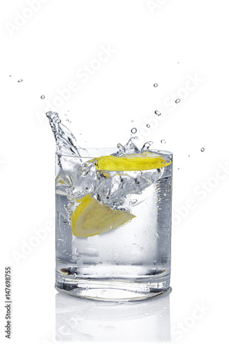 Ice cube and lemon splashing cocktail in oldfashioned glass. Drink with splashing citrus isolated on white.