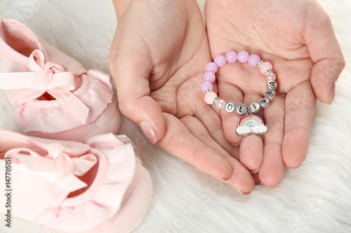 Bracelet with baby name Olivia in hands on white fluffy background