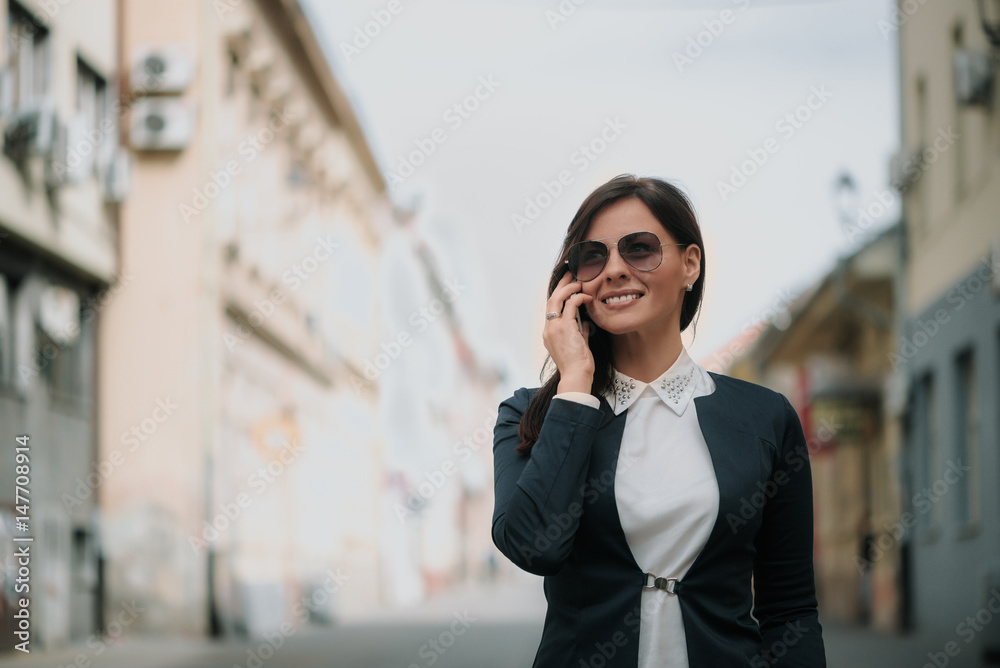 Young Woman Walking the City Talking to Someone on her Mobile Phone While Looking Into the Distance with Happy Facial Expression