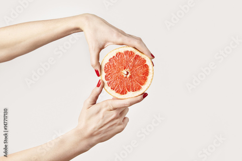 Juicy fresh grapefruit in a beautiful woman's hands isolated on white