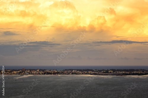 Big clouds with sunset over city and sea before storm.