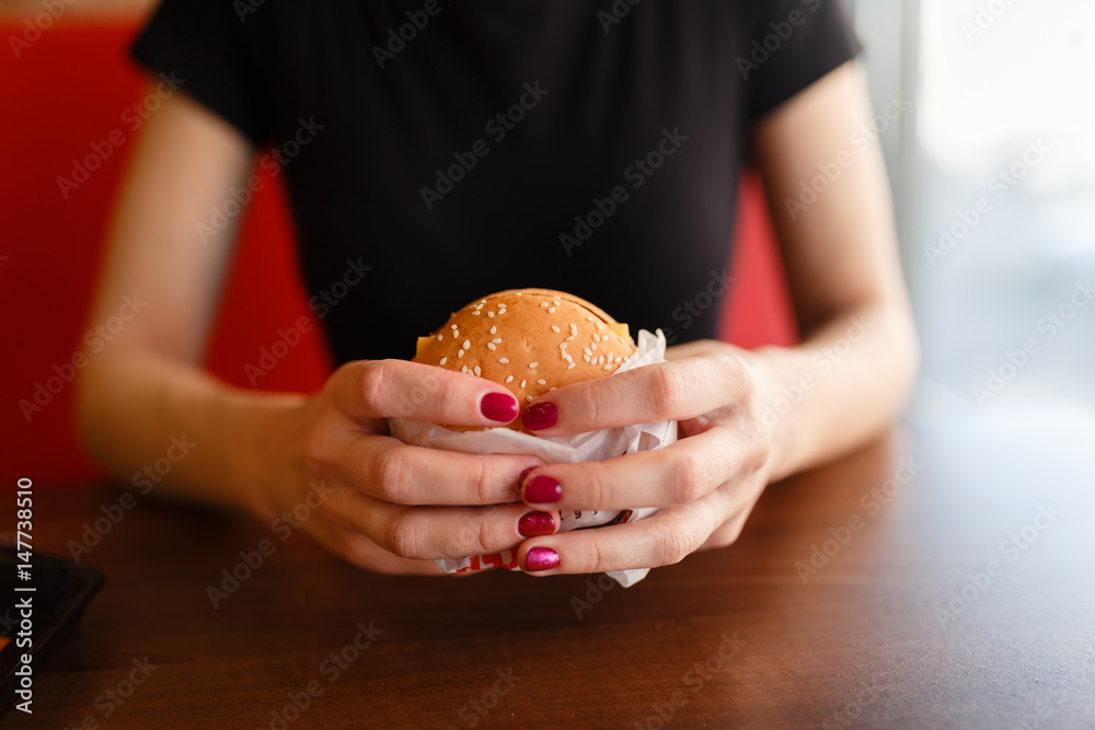 Young girl holding in female hands fast food burger, american unhealthy calories meal on background, mockup with copy space for text message design, hungry human with grilled hamburger front view Young girl holding in female hands fast food burger, american unhealthy calories meal on background, mockup with copy space for text message design, hungry human with grilled hamburger front view