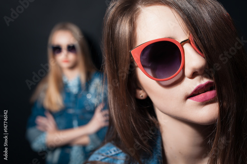two stylish hipster girls in sunglasses posing;