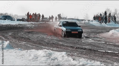 Rally car goes on dirt. ars go off-roading in race. Rally car going down slope in race at Sun City. Dirty rural road with puddles and mud under dark dramatic stormy sky, SUV car goes far away. photo