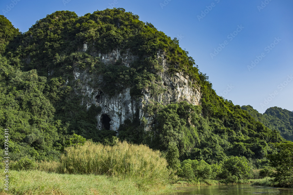 Green mountain with sandstone rock face, Ninh Binh, Vietnam